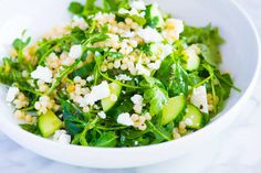 a white bowl filled with cucumber, spinach and feta cheese salad