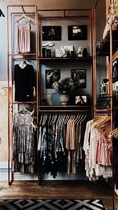 an open closet with clothes and pictures on the wall, hanging from metal racks in front of it