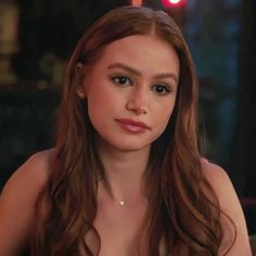 a young woman with long hair is looking at the camera while she's sitting down