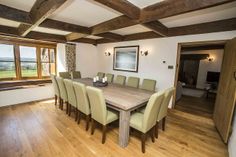 a large wooden table surrounded by green chairs in a room with wood beams on the ceiling