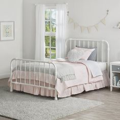 a white bed sitting next to a window on top of a carpeted bedroom floor