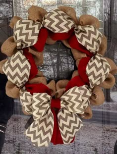 a wreath with burlocks and red ribbon hanging on the front door