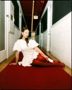 a woman is sitting on the floor with her legs crossed and wearing red tights