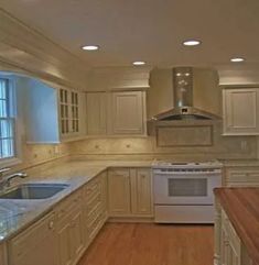 an empty kitchen with wood floors and white cabinets