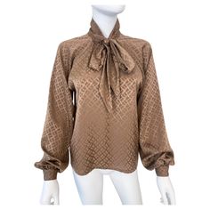 Wonderful vintage 1980s silky polyester pussy bow blouse in a peasant-style silhouette with attached scarf-bow. Cocoa brown color fabric with tone-on-tone geometric pattern. The pullover construction has a partially open front with a metal hook at the collar. Long raglan sleeves slightly puffed at the wrist and closed with a button. Brand: Unknown. Model: Polyester shirt. Material: polyester, synthetic (estimate) Dominant Color: Brown. Pattern: Tone-on-tone print. Closure: Hook on the front. CON Scarf Bow, Polyester Shirt, Brown Pattern, Cocoa Brown, Peasant Style, Bow Blouse, Color Fabric, Brand Tags, Blouse Top