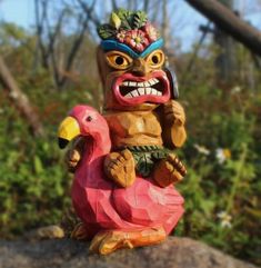 a totema sitting on top of a rock next to a pink flamingo