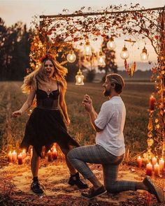 a man kneeling down next to a woman in front of an arch with candles on it