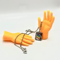 a yellow glove with chain and tag attached to it on a white surface, next to a pair of orange rubber gloves