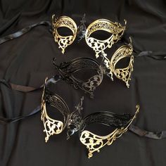 These Masquerade masks are hand Painted gold and black and have a unique design.  Masks are made of a lightweight metal and have silk ribbon ties attached. Stand out at your next Masquerade ball or mask costume party with this elegant mask.  Three styles to choose from also available in silver.  Mask size 6"W x 3"H. Style gold and black metal masks. By Essance Masquerade Elegant Gold Masks And Prosthetics For Party, Elegant Gold Costume Accessories For Party, Gold Mask For Masquerade, Gold Masks For Halloween Costume Party, Elegant Gold Party Masks And Prosthetics, Gold Adjustable Costume Accessories For Costume Party, Gold Adjustable Costume Accessories For Party, Gold Mask For Mardi Gras Evening, Gold Masks For Mardi Gras Evening Events