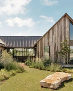 a wooden house with a stone bench in the front yard