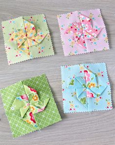 four square pieces of fabric with flowers and bows on them sitting on top of a table