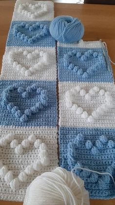 two crocheted squares with balls of yarn next to them