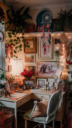 a desk with some pictures on the wall and plants hanging above it in front of a window