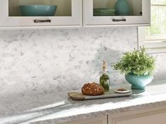 a kitchen counter with two glass cabinets above it and a bottle of wine on the counter