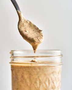 a spoon full of peanut butter on top of a jar