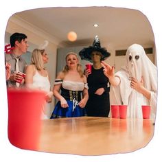 a group of people dressed up as ghostes and witches at a party with drinks