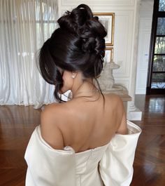 a woman in a white dress is looking down at her hair and shoulder length bun