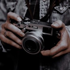 a person holding a camera in their hands with one hand and the other on his hip