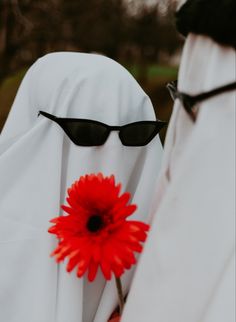 two people dressed in white with sunglasses and a red flower