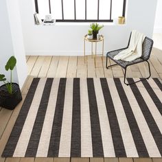 a black and white striped rug in a room with a chair next to a potted plant