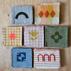 four squares with different designs on them sitting next to each other in front of a wooden surface