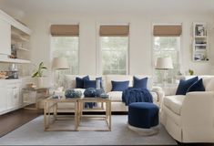 a living room filled with white furniture and blue pillows