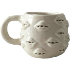 a white ceramic mug with holes in the middle and eyes on it's side