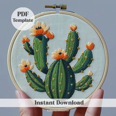 a hand is holding up a small embroidery kit with an image of a cactus on it