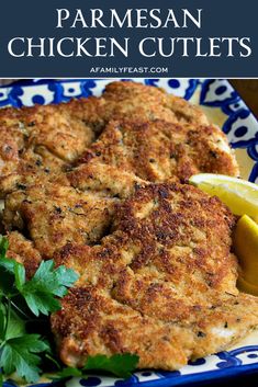 parmesan chicken cutlets on a blue and white plate with lemon wedges