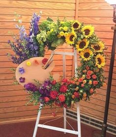 an easel with flowers and paintbrush on it