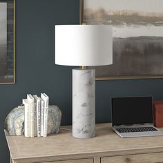 a laptop computer sitting on top of a wooden desk next to a lamp and books