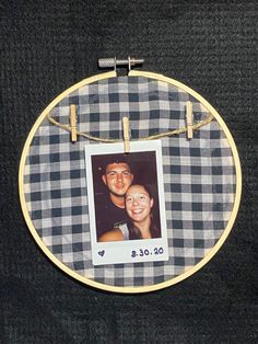 a photo hanging on a rope with a wooden frame and string attached to it, in front of a black background