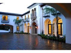 a large white house with lots of windows and palm trees in the front yard at night