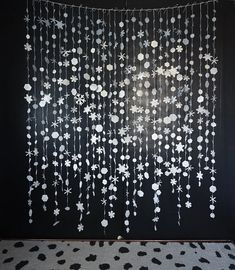 a black wall with white flowers hanging from it's side and a polka dot rug on the floor