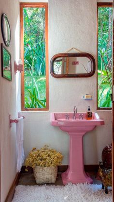 a bathroom with a pink sink, mirror and rug on the floor in front of it