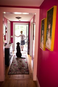 a woman is standing in the hallway with her dog and looking into the room through the door