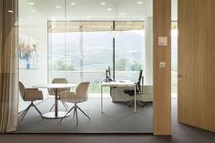 an office with glass walls and desks in front of a large window that looks out onto the mountains