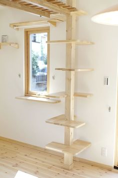 an empty room with wooden shelves on the wall, and a window in the corner