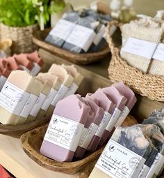 soaps are displayed on wooden trays in front of baskets with flowers and plants