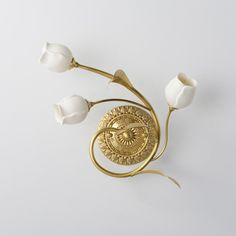 a gold brooch with three white flowers on it