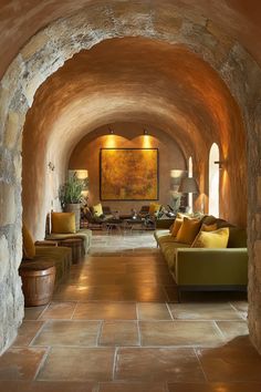 a living room filled with lots of furniture and walls covered in stone archways that lead into the dining area