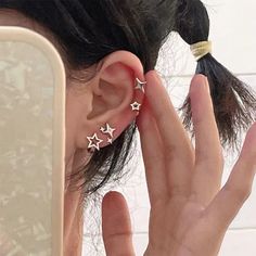 a woman is holding her ear with three stars in the middle and one behind her ear