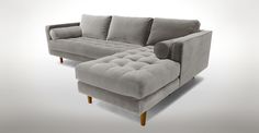 a blue velvet couch and ottoman with wooden legs in front of a white background,