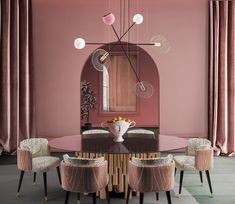 an elegant dining room with pink walls and chairs around a round glass table surrounded by gold accents