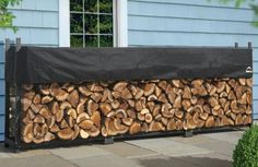 a large pile of logs sitting in front of a blue house