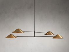 three brass colored lights hanging from a ceiling fixture in a room with concrete walls and flooring