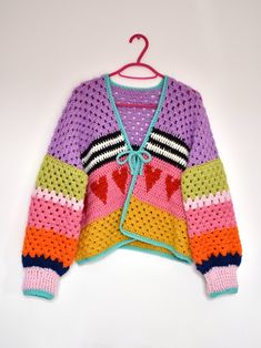 a colorful knitted sweater hanging on a hanger with the word love written across it