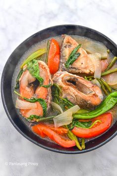 a pan filled with fish and vegetables on top of a table