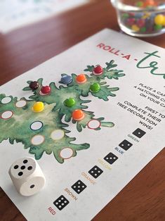 a board game with dices and candy on the table next to it is called roll - a - tree