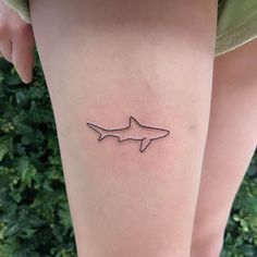 a woman's leg with a small tattoo of a shark on the side of her thigh